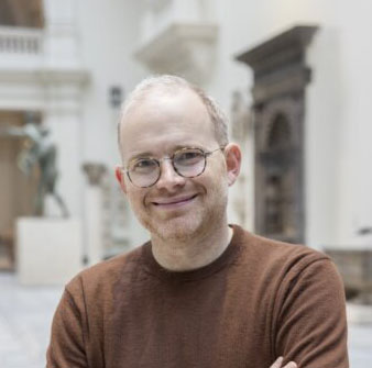 A man smiling standing at the V&A