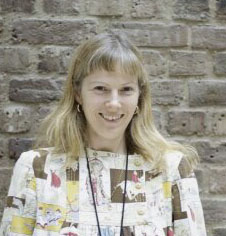 A woman smiling standing against a brick wall