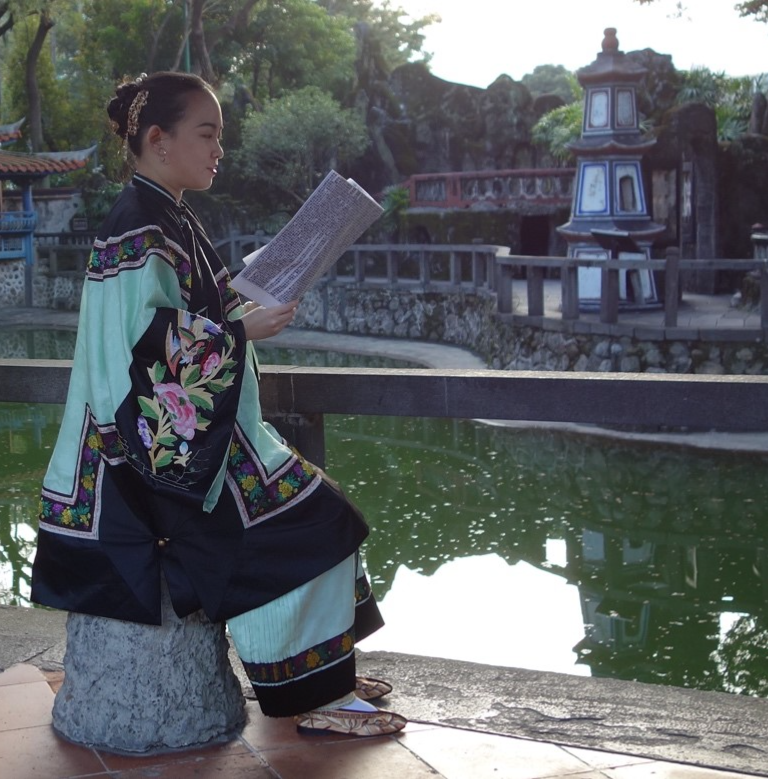 Laurence Wen-Yu Li reading in front of a pool of water